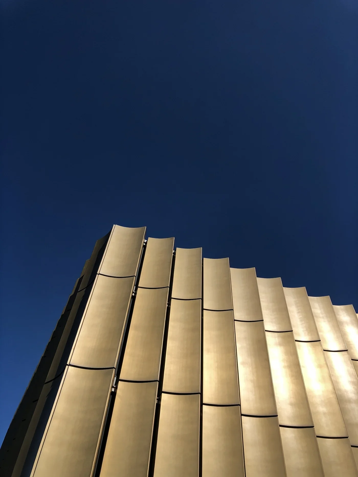 Designkonzept für einen Metallbaubetrieb: eine gefaltete Metallfassade vor dunklem Himmel.